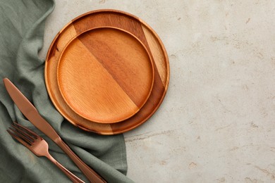Photo of Stylish setting with cutlery, napkin and plates on light table, top view. Space for text
