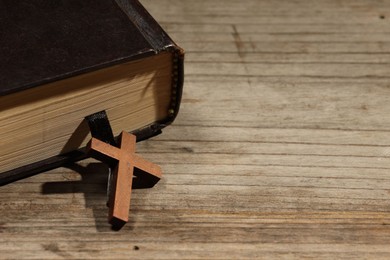 Photo of Bible and cross on wooden table, closeup with space for text. Religion of Christianity