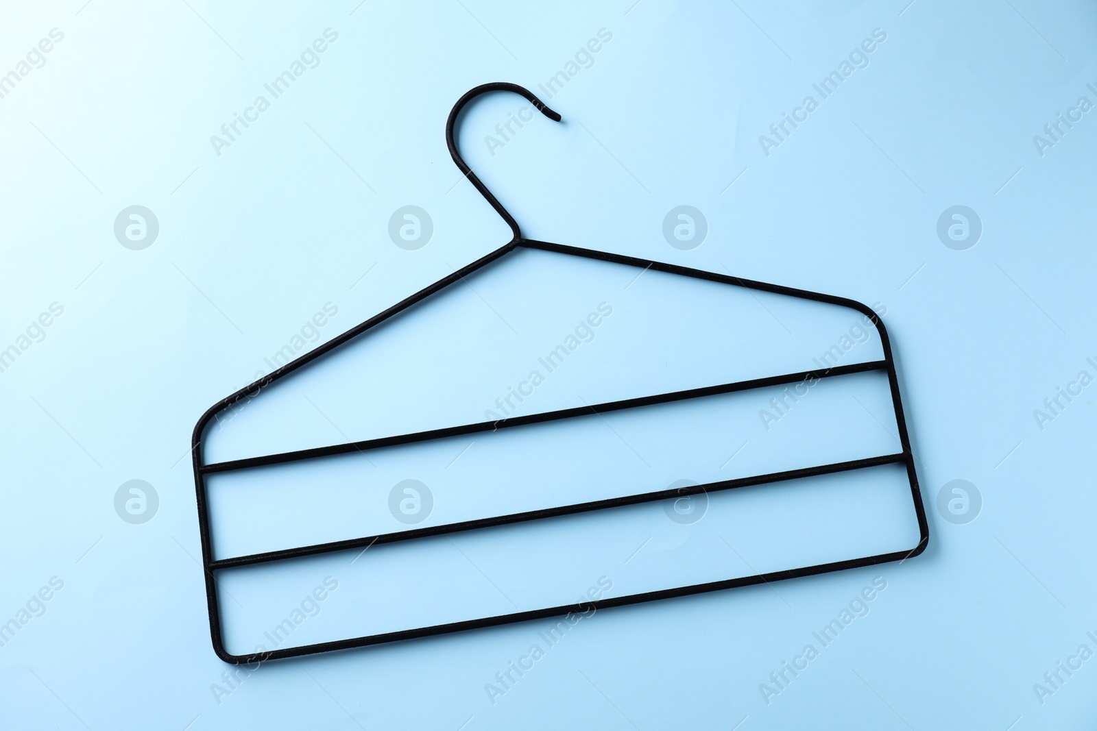 Photo of One black hanger on light blue background, top view