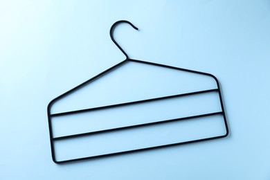 One black hanger on light blue background, top view