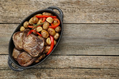 Photo of Tasty beef tongue pieces with potatoes, pepper and rosemary on wooden table, top view. Space for text