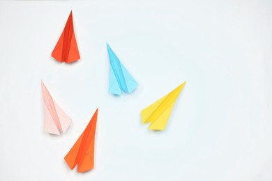 Photo of Handmade colorful paper planes on white table, flat lay. Space for text