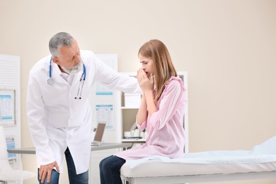 Coughing teenage girl visiting doctor at clinic