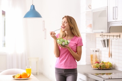 Photo of Woman eating vegetable salad in kitchen. Healthy diet