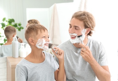 Photo of Father and son shaving together in bathroom