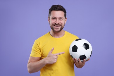 Photo of Happy sports fan with ball on purple background