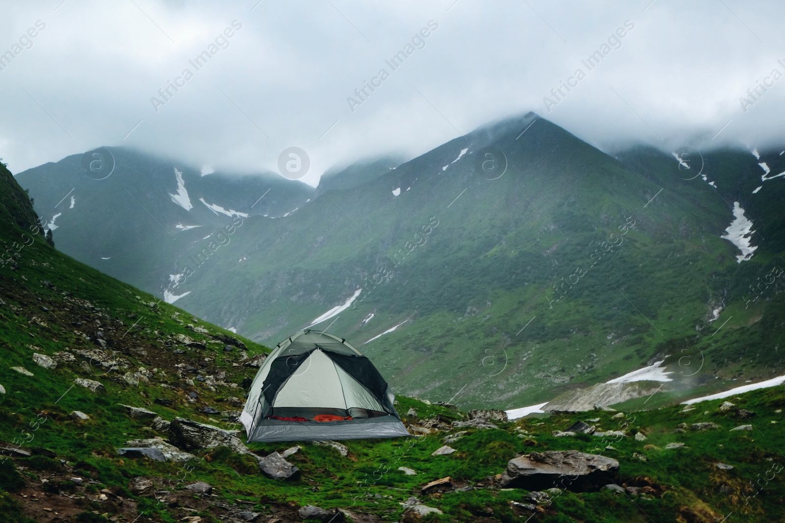 Image of Camping tent with sleeping bags near beautiful foggy mountains