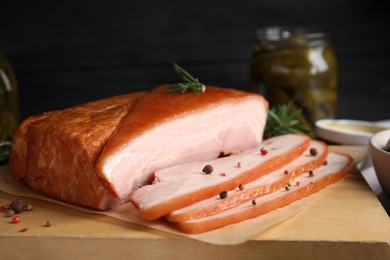 Photo of Delicious smoked bacon with rosemary and peppercorns on wooden board, closeup