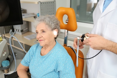 Photo of Professional otolaryngologist examining senior woman with endoscope in clinic. Hearing disorder