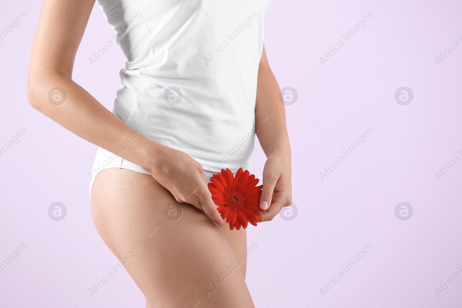 Photo of Young woman holding flower near underwear on color background. Gynecology