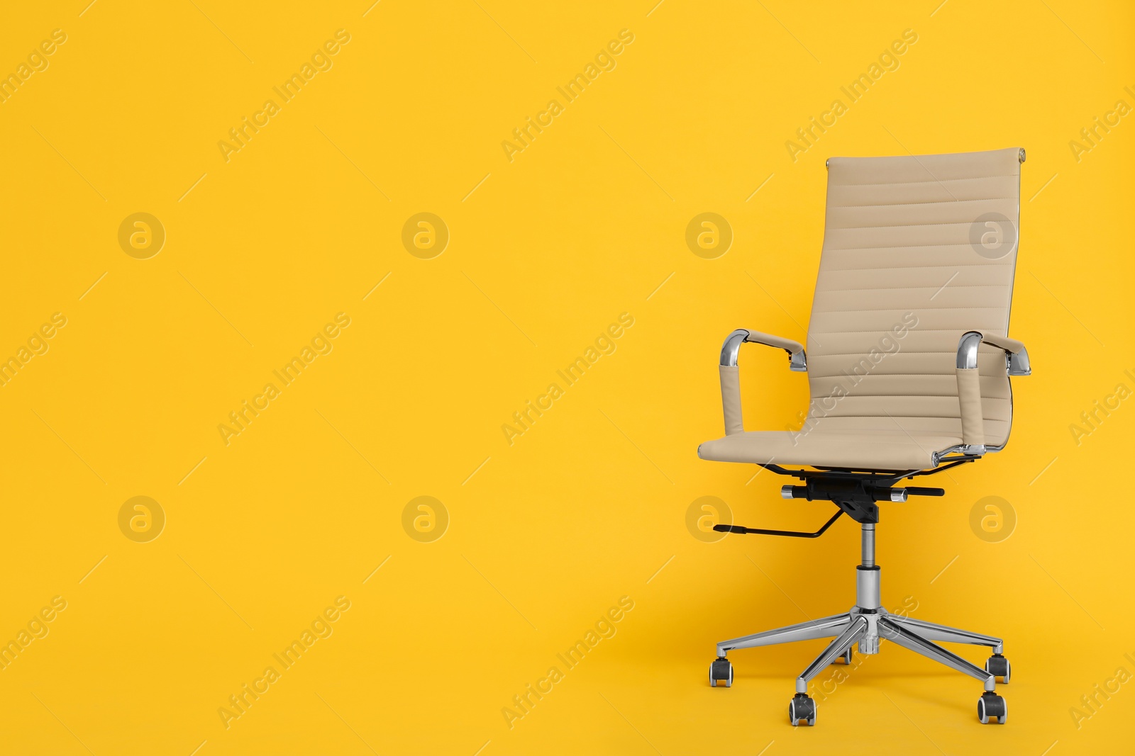 Photo of Modern office chair on yellow background. Space for text