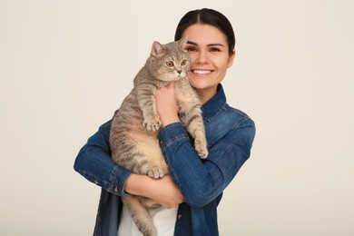 Photo of Young woman with adorable cat on light background