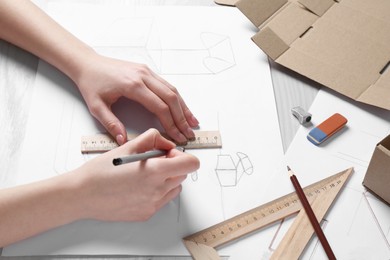 Photo of Woman creating packaging design at light wooden table, closeup