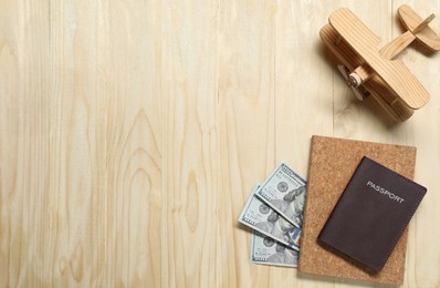 Photo of Flat lay composition with dollars, model of plane and passport on wooden table, space for text. Business trip