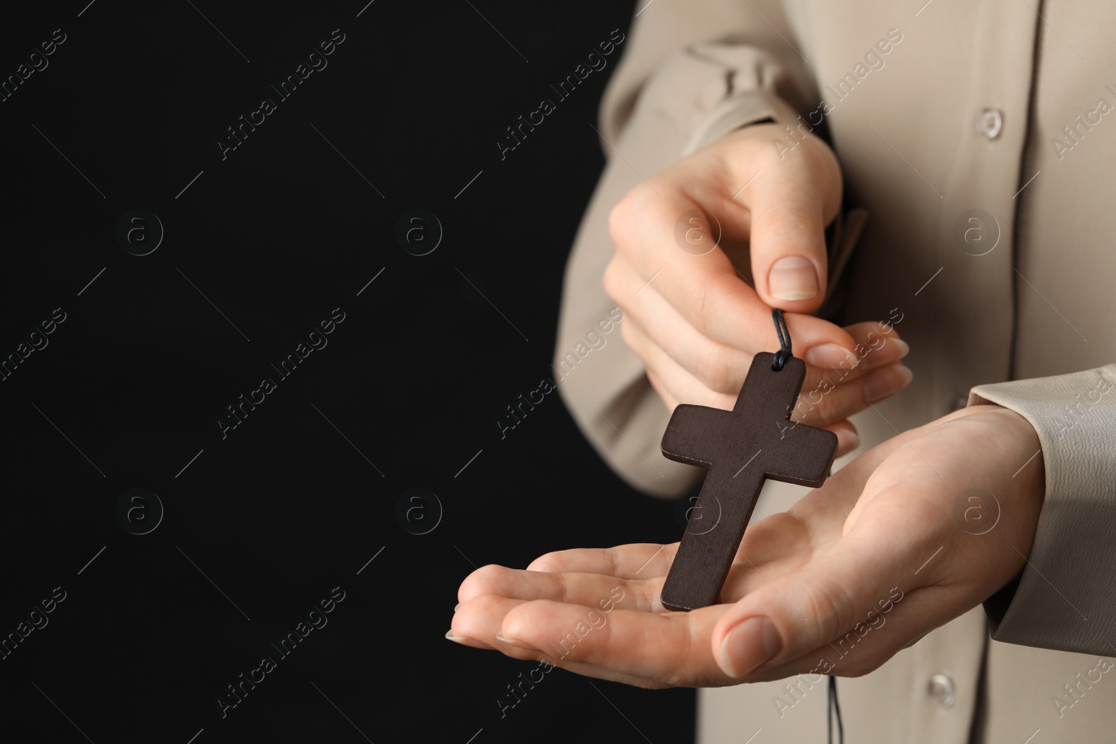 Photo of Woman holding wooden Christian cross on black background, closeup. Space for text