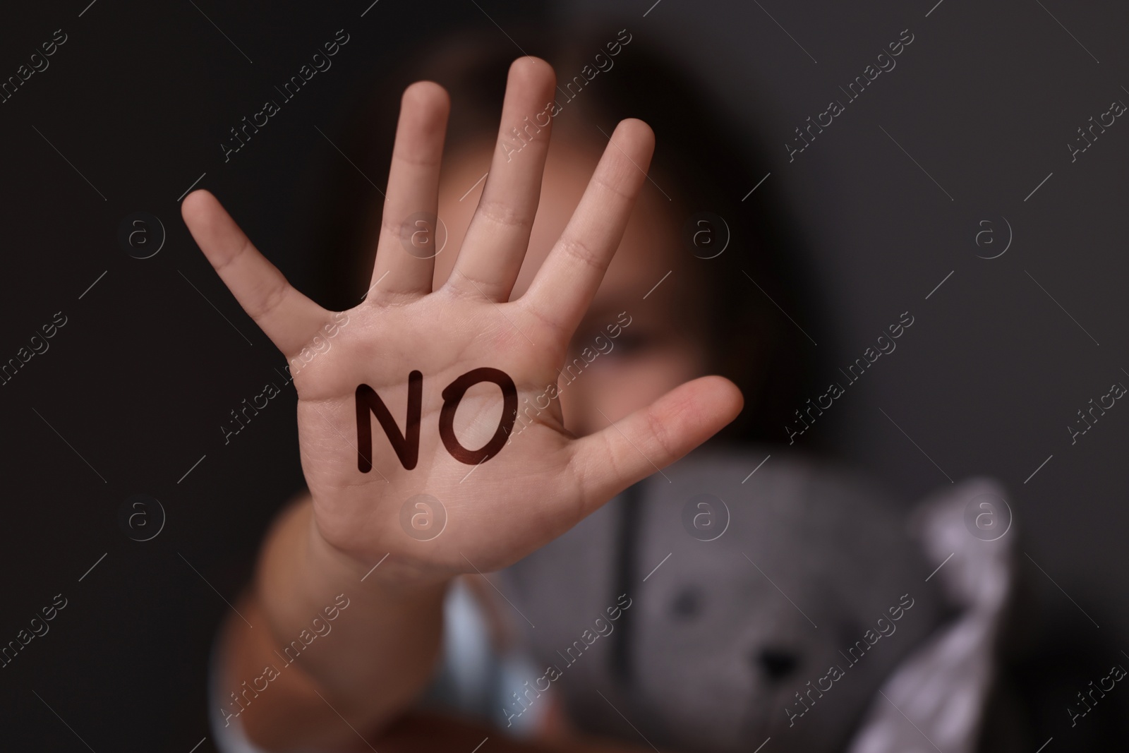 Image of Child abuse. Little girl making stop gesture on dark background, selective focus. No written on her hand