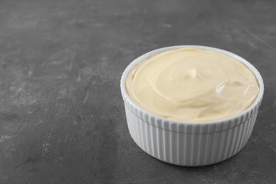 Photo of Fresh mayonnaise sauce in bowl on grey table. Space for text