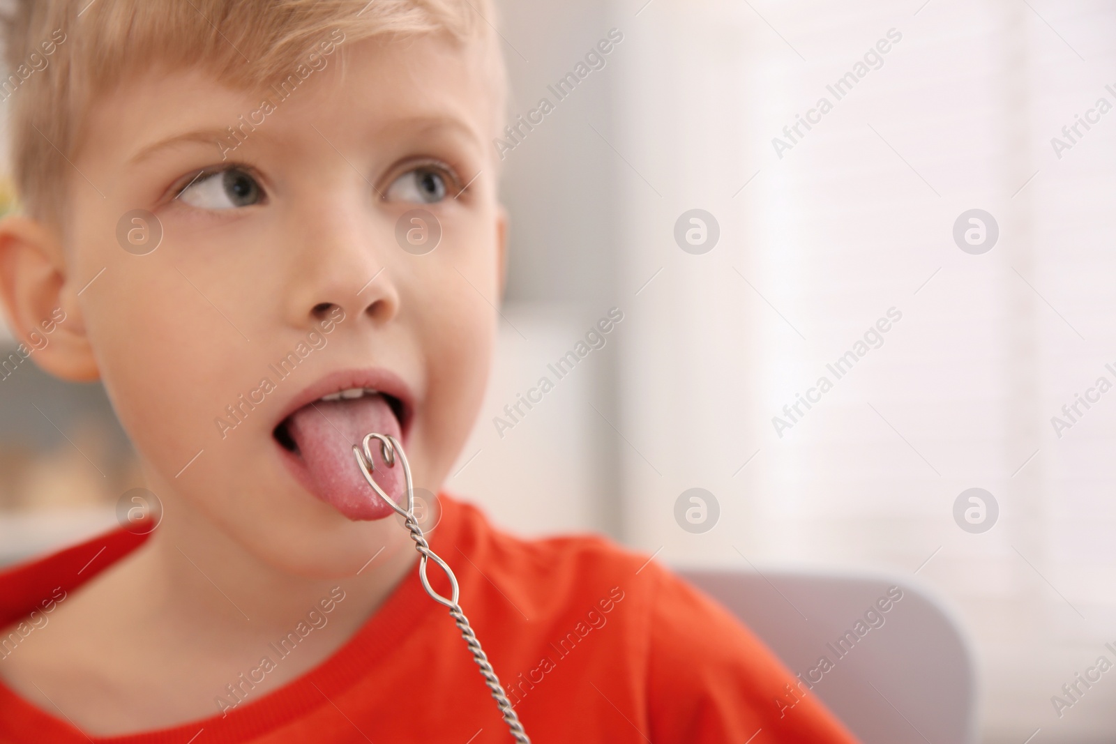 Photo of Little boy doing exercise with logopedic probe at speech therapist office, closeup