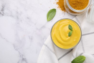 Photo of Tasty curry sauce, powder and basil leaves on white marble table, flat lay. Space for text