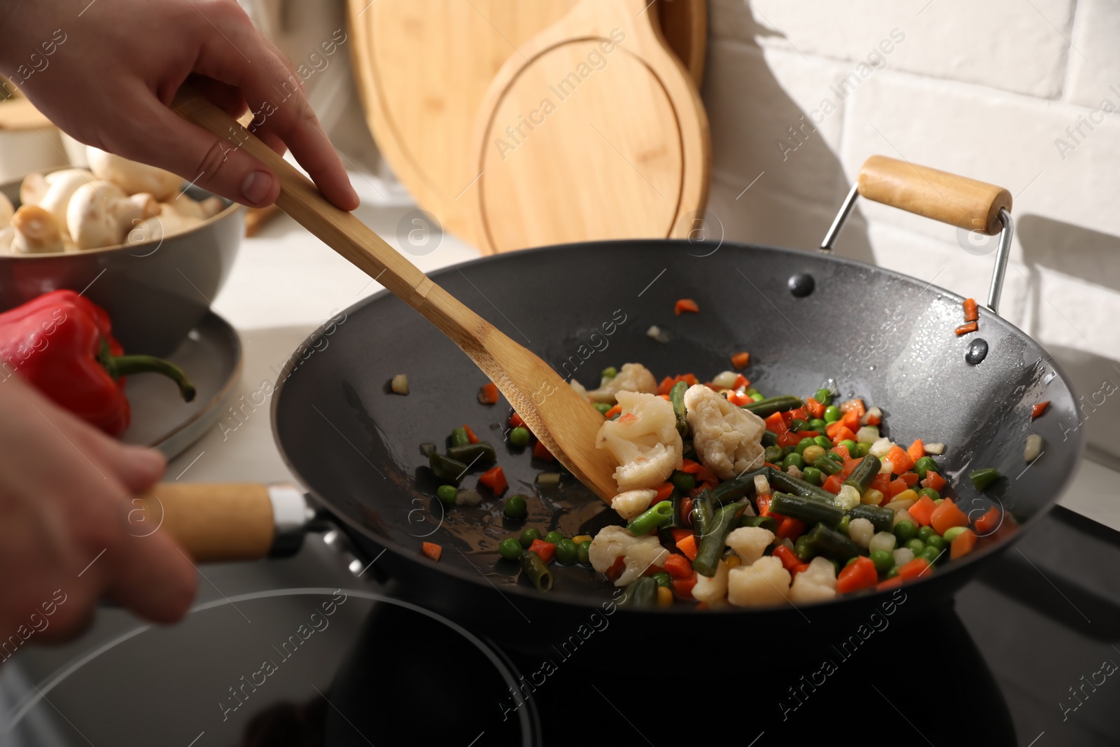 Photo of Man stirring mix of fresh vegetables in frying pan, closeup