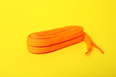 Photo of Orange shoe lace on yellow background. Stylish accessory