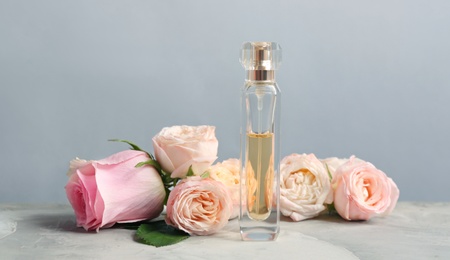 Bottle of perfume with beautiful roses on table