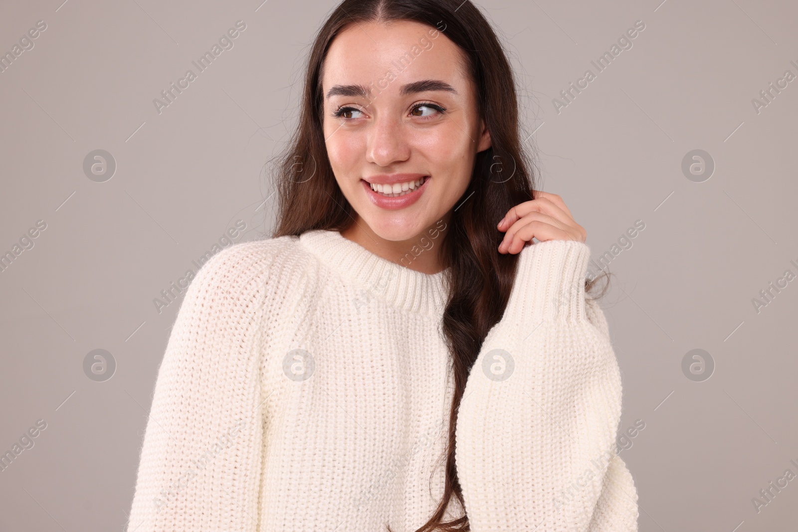 Photo of Beautiful young woman in stylish warm sweater on grey background