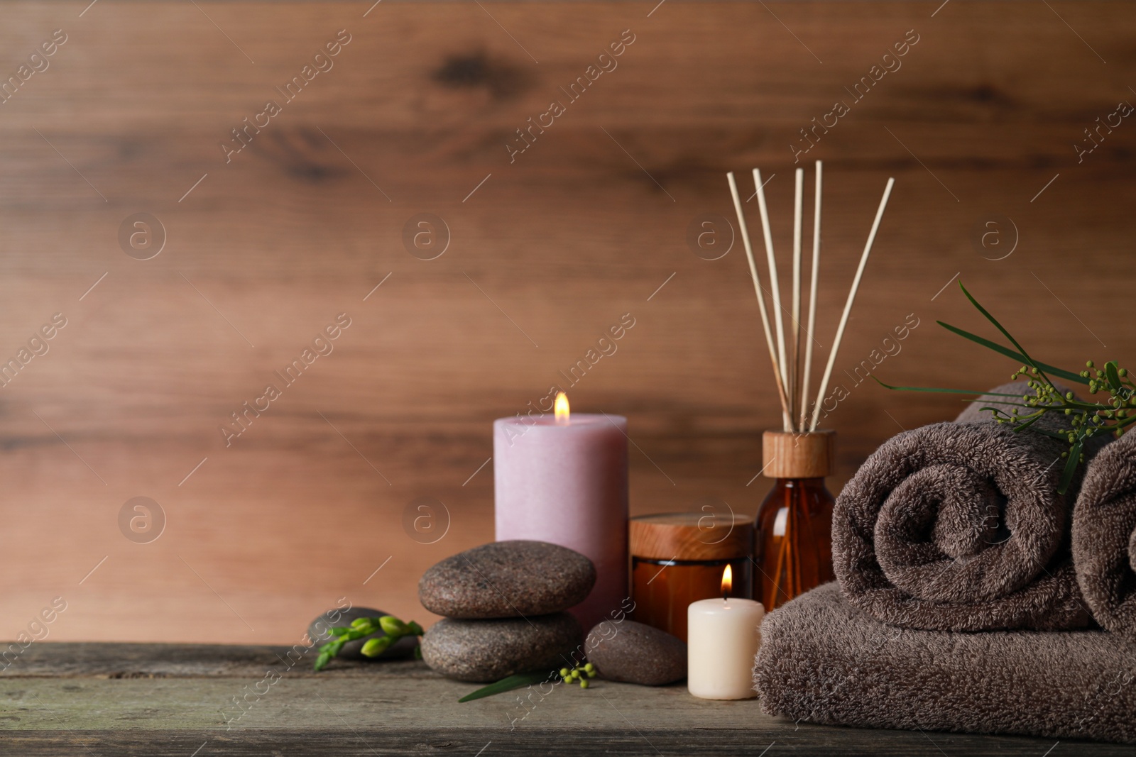 Photo of Beautiful spa composition with different care products and burning candles on wooden table. Space for text