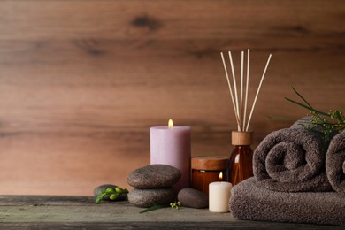 Photo of Beautiful spa composition with different care products and burning candles on wooden table. Space for text