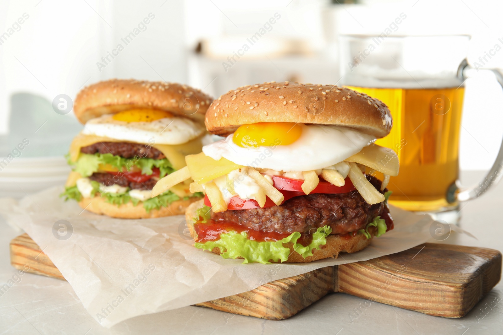 Photo of Tasty burgers with fried egg on wooden board