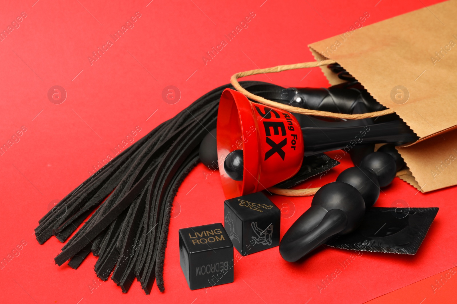 Photo of Shopping bag and different sex toys on red background