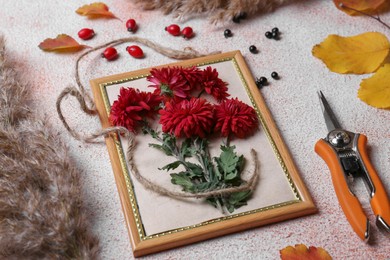 Photo of Composition with secateurs, twine and Chrysanthemum flowers on light textured table