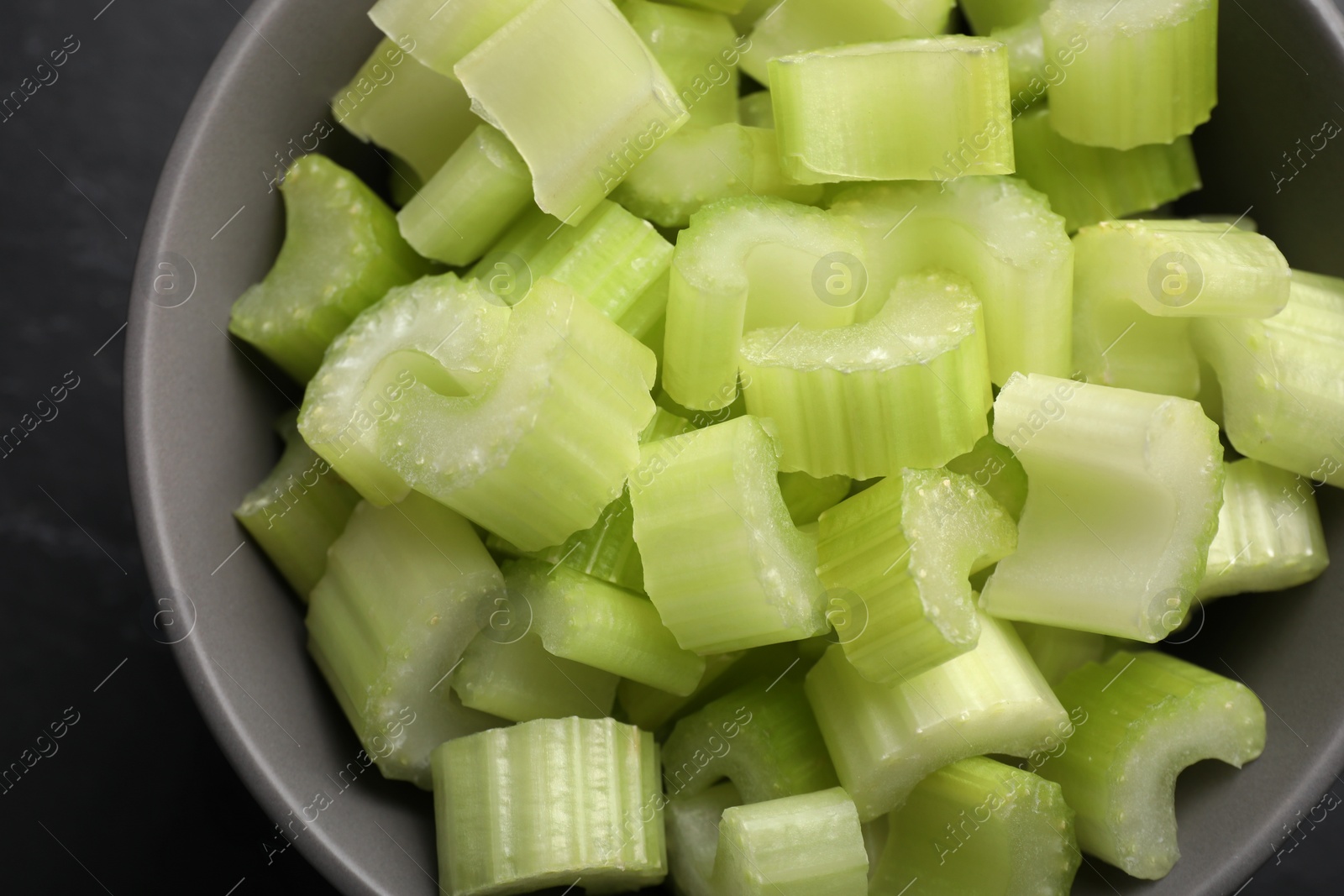 Photo of One bowl of fresh cut celery on grey table, top view