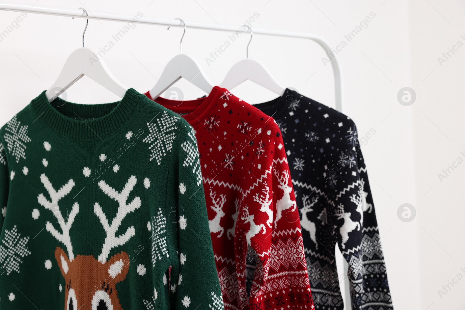 Photo of Rack with different Christmas sweaters on white background