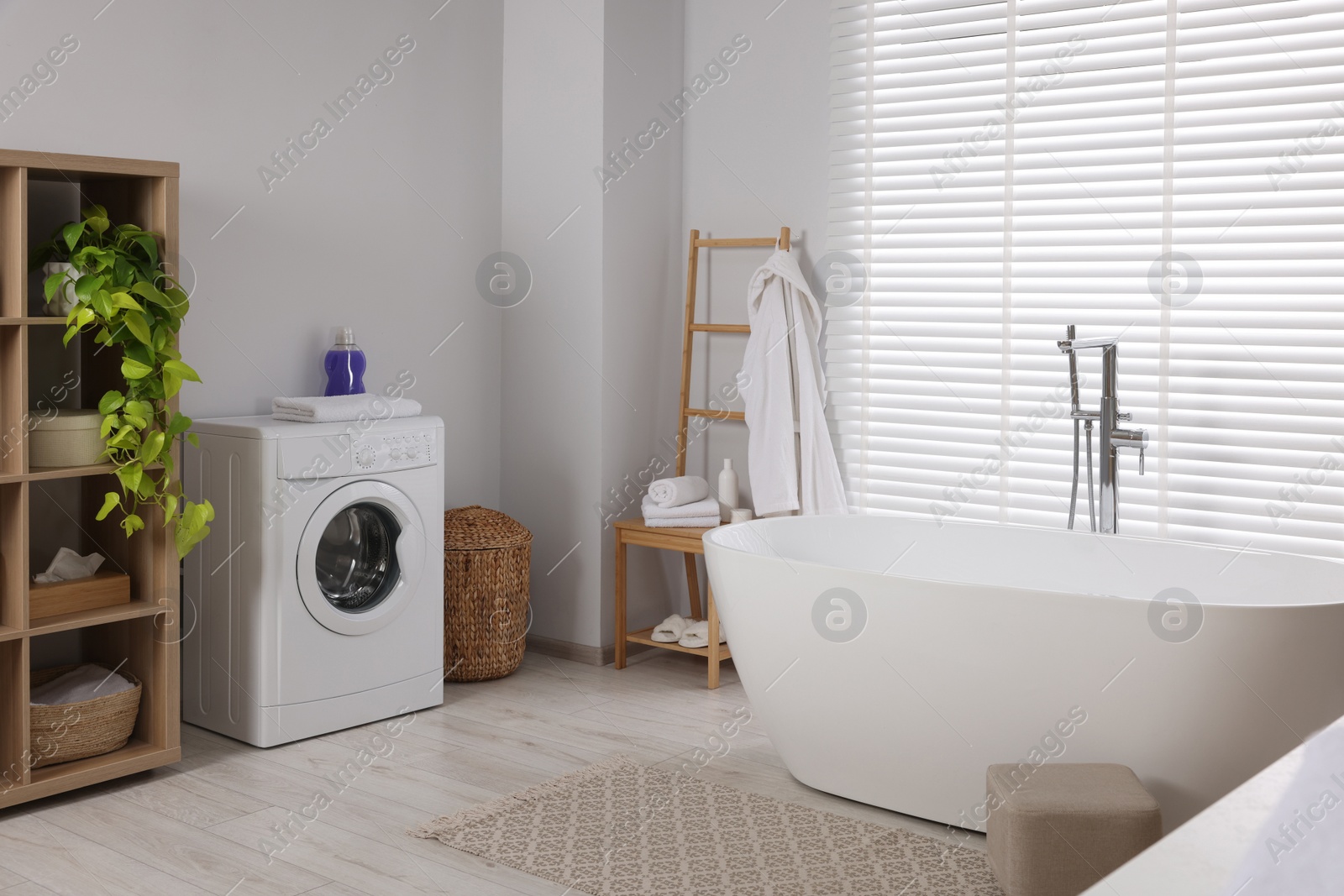 Photo of Stylish bathroom interior with beautiful tub, washing machine and decor elements