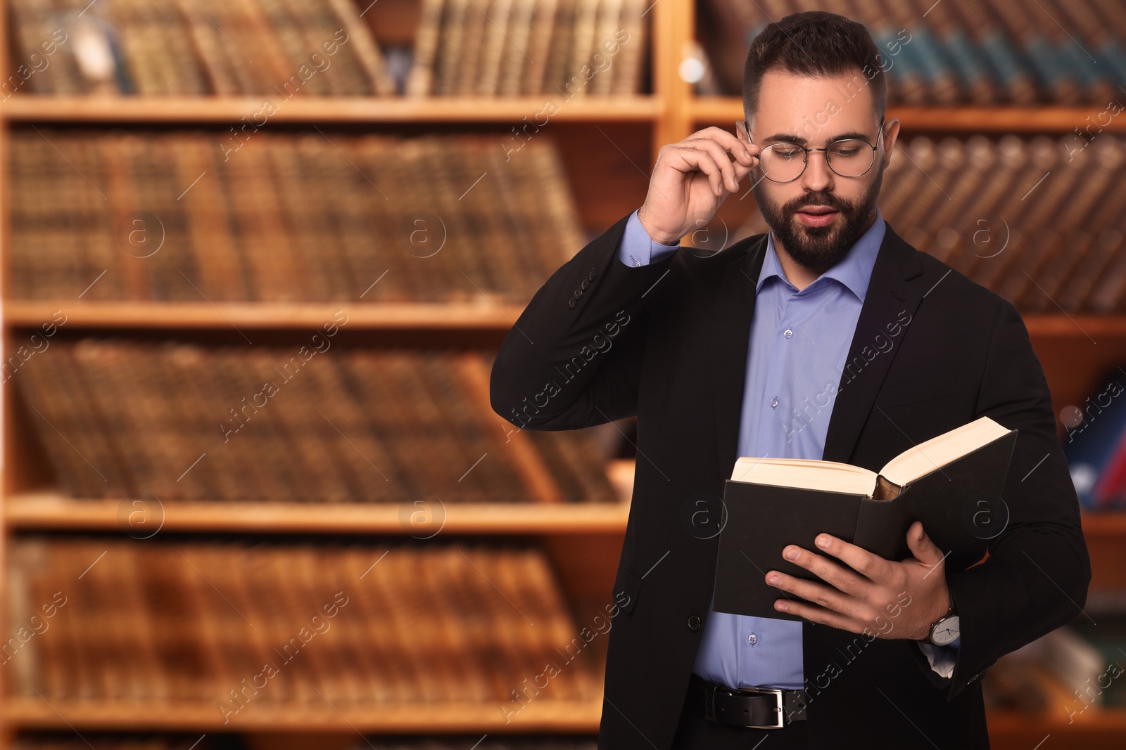 Image of Confident lawyer in glasses reading book in office, space for text