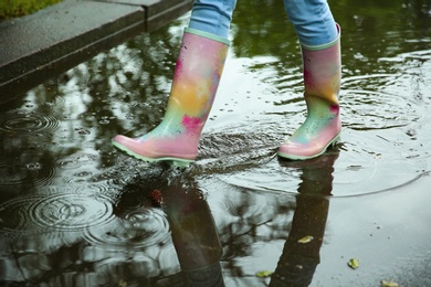 Photo of Woman with rubber boots in puddle, closeup. Rainy weather