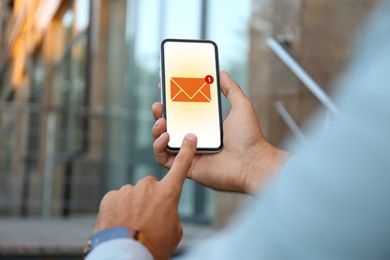 Image of Man checking new message on mobile phone outdoors, closeup