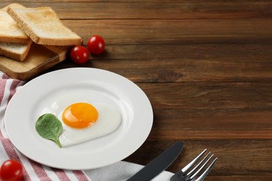 Photo of Romantic breakfast with heart shaped fried egg served on wooden table, space for text