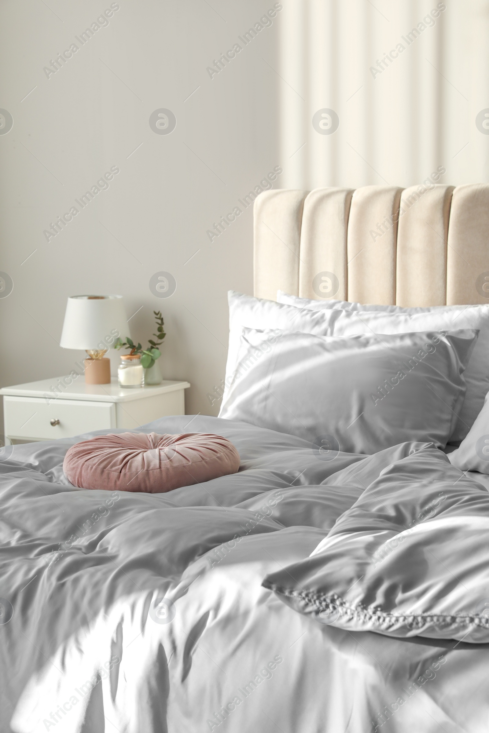 Photo of Bed with stylish silky linens in room