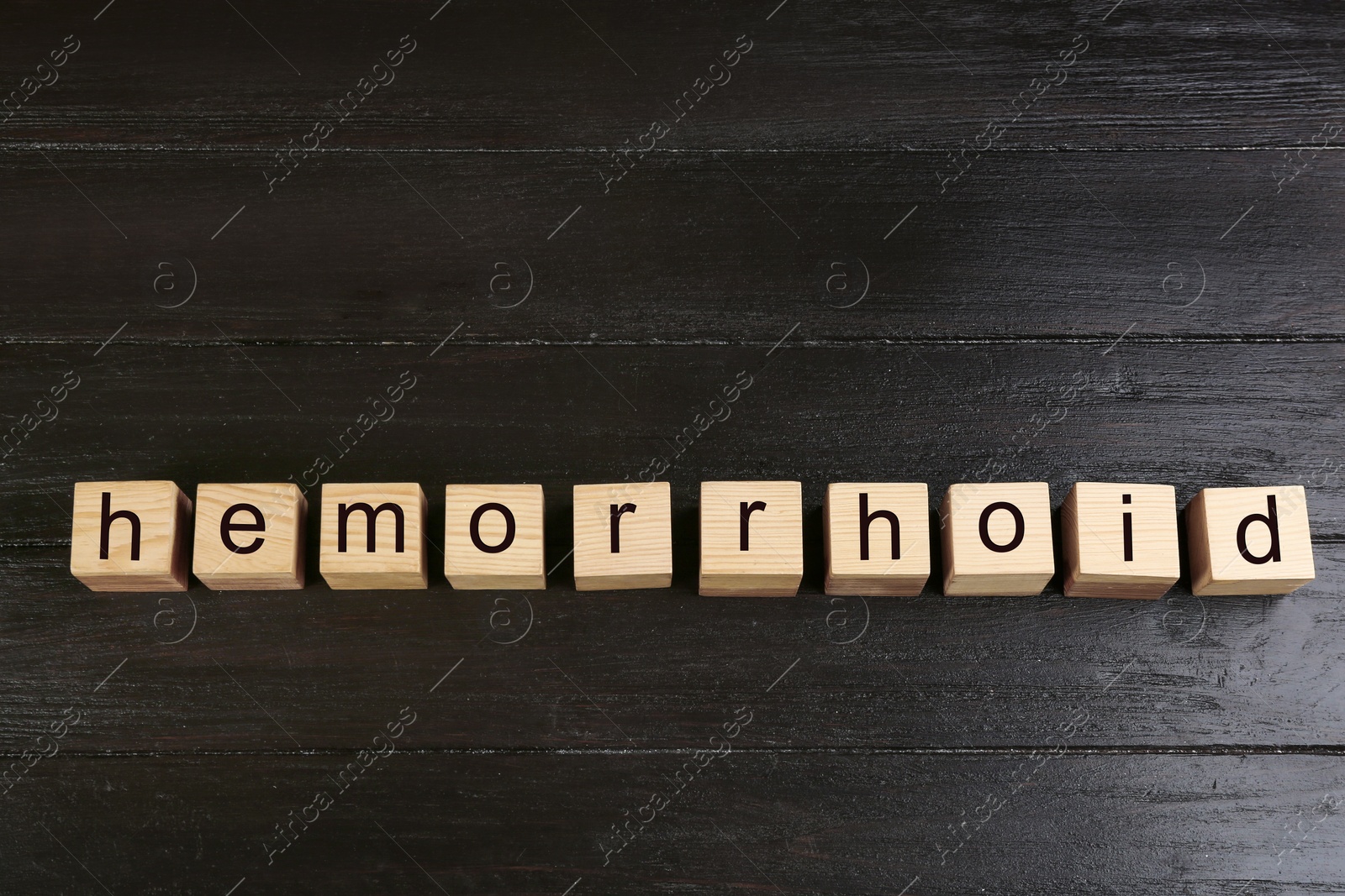 Photo of Wooden cubes with word HEMORRHOID on black table, top view