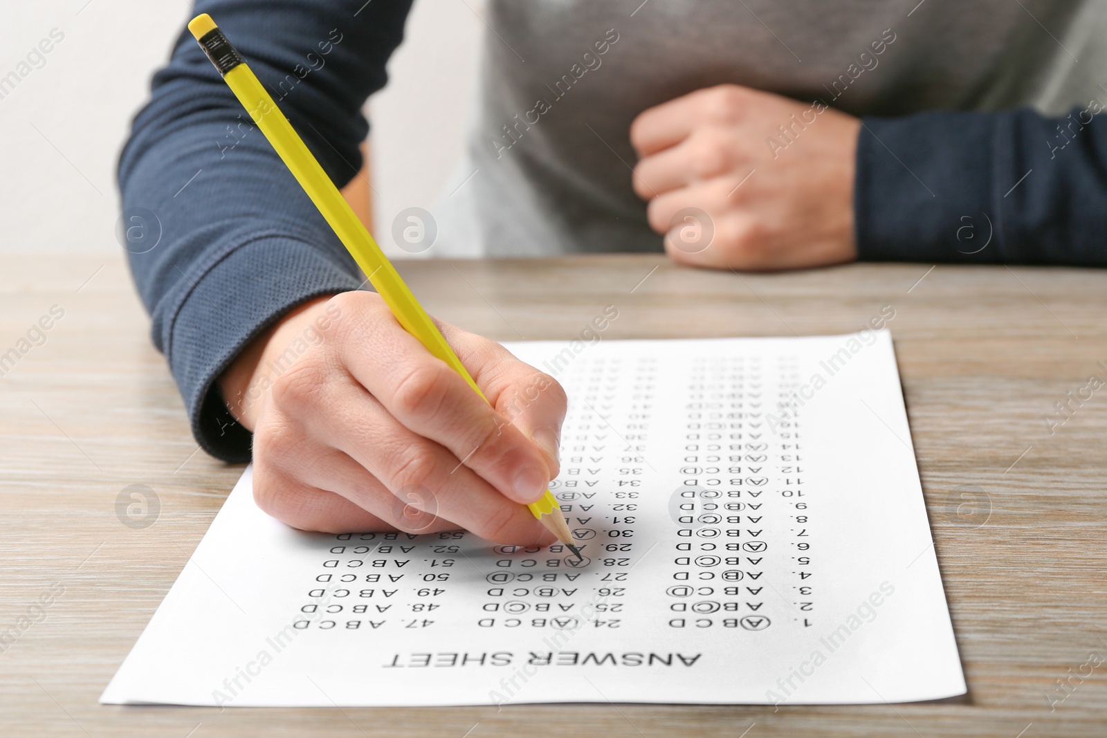 Photo of Student filling answer sheet at table, closeup