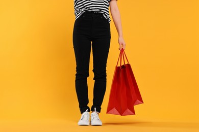 Photo of Woman with shopping bags on yellow background, closeup