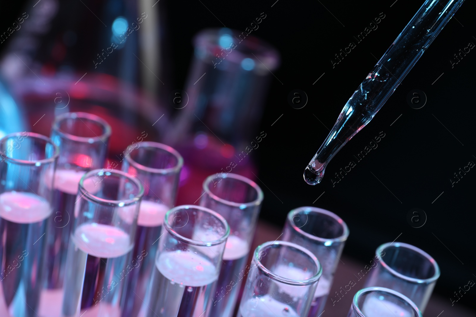 Photo of Dripping reagent into test tube on black background, closeup. Laboratory analysis