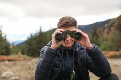 Photo of Boy looking through binoculars in beautiful mountains