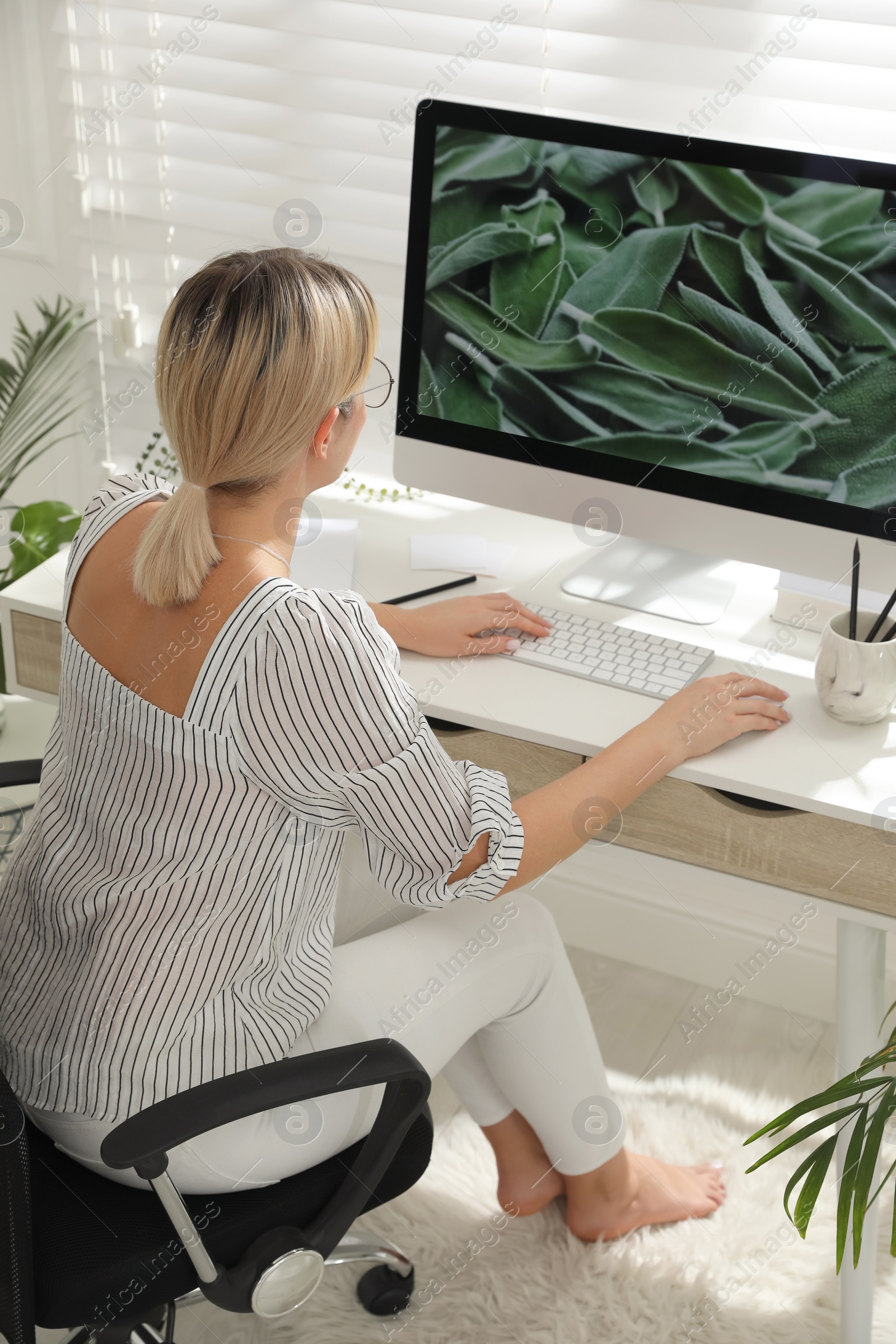 Photo of Woman working on computer at table in room. Interior design