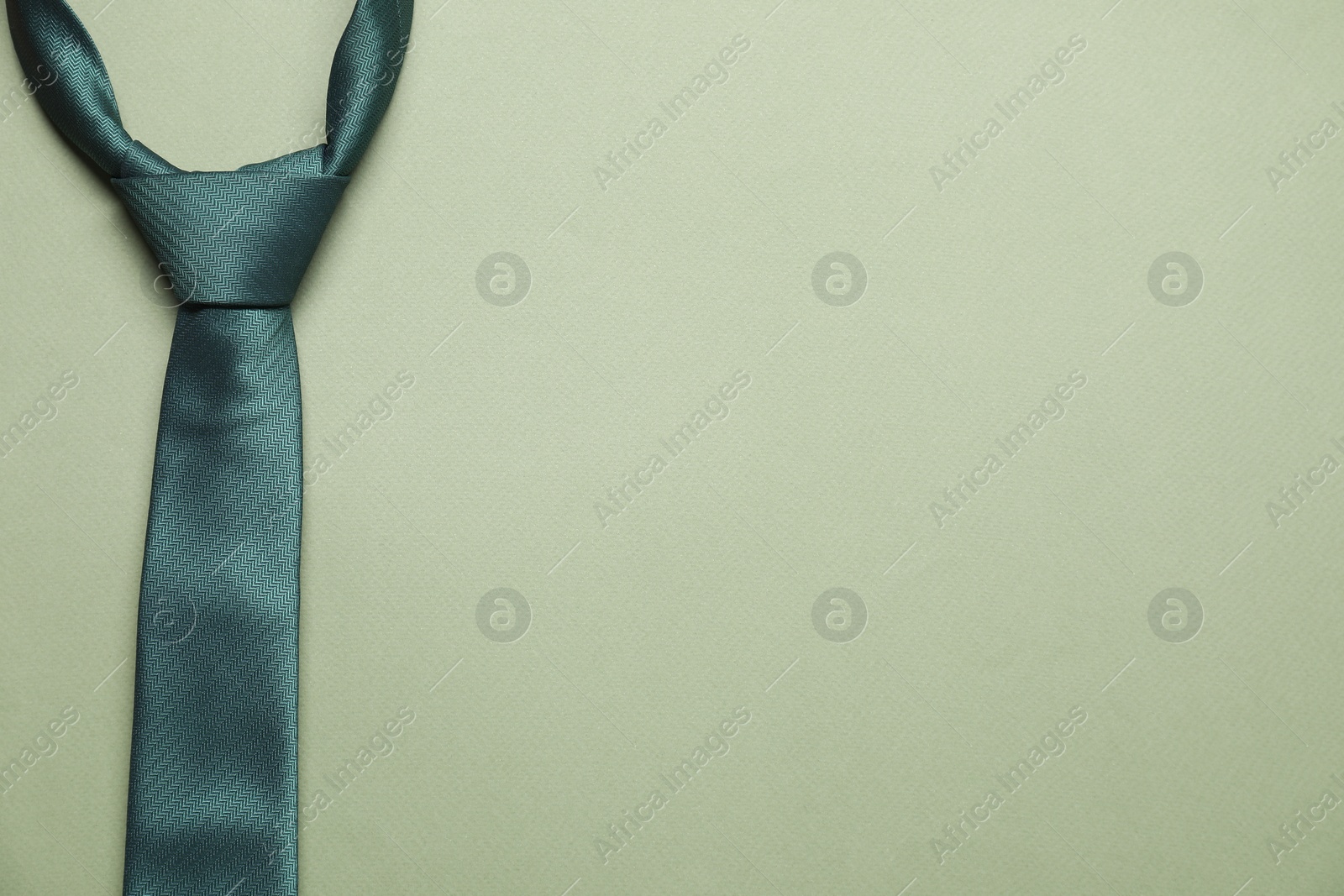 Photo of Stylish necktie on light green background, top view. Space for text