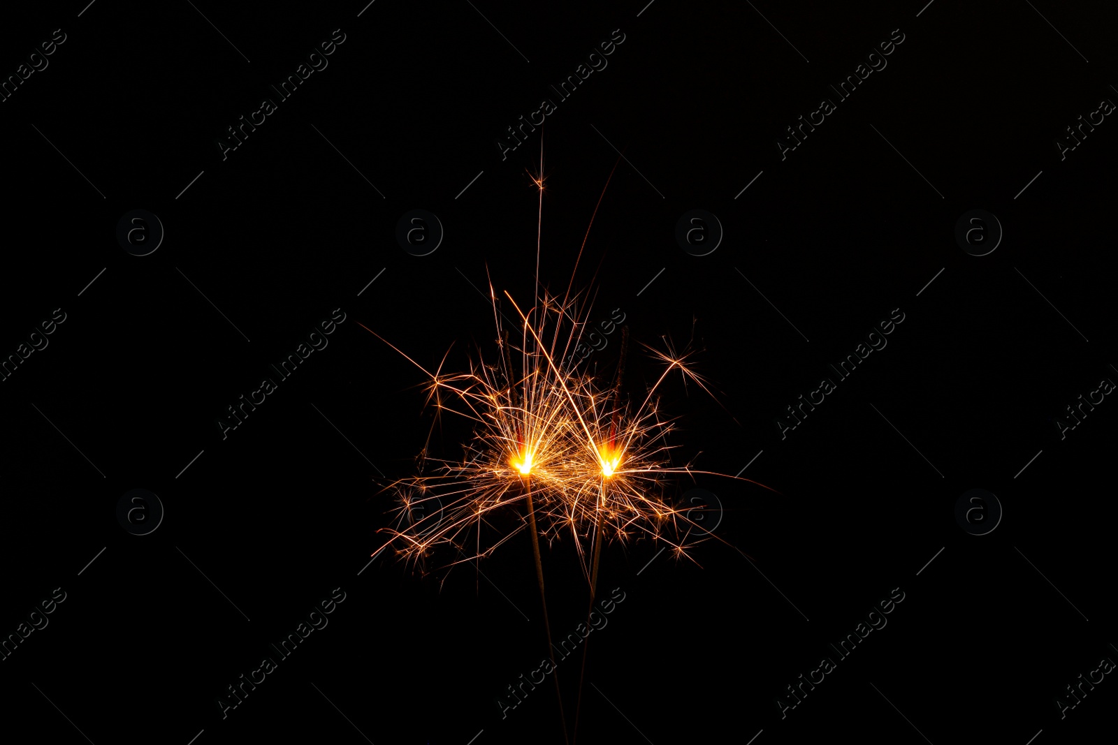 Photo of Two burning sparkler sticks glowing in dark