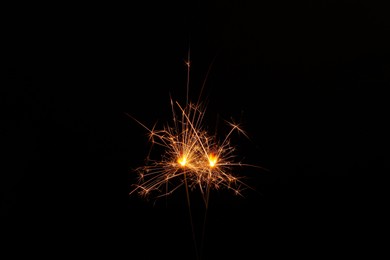 Photo of Two burning sparkler sticks glowing in dark