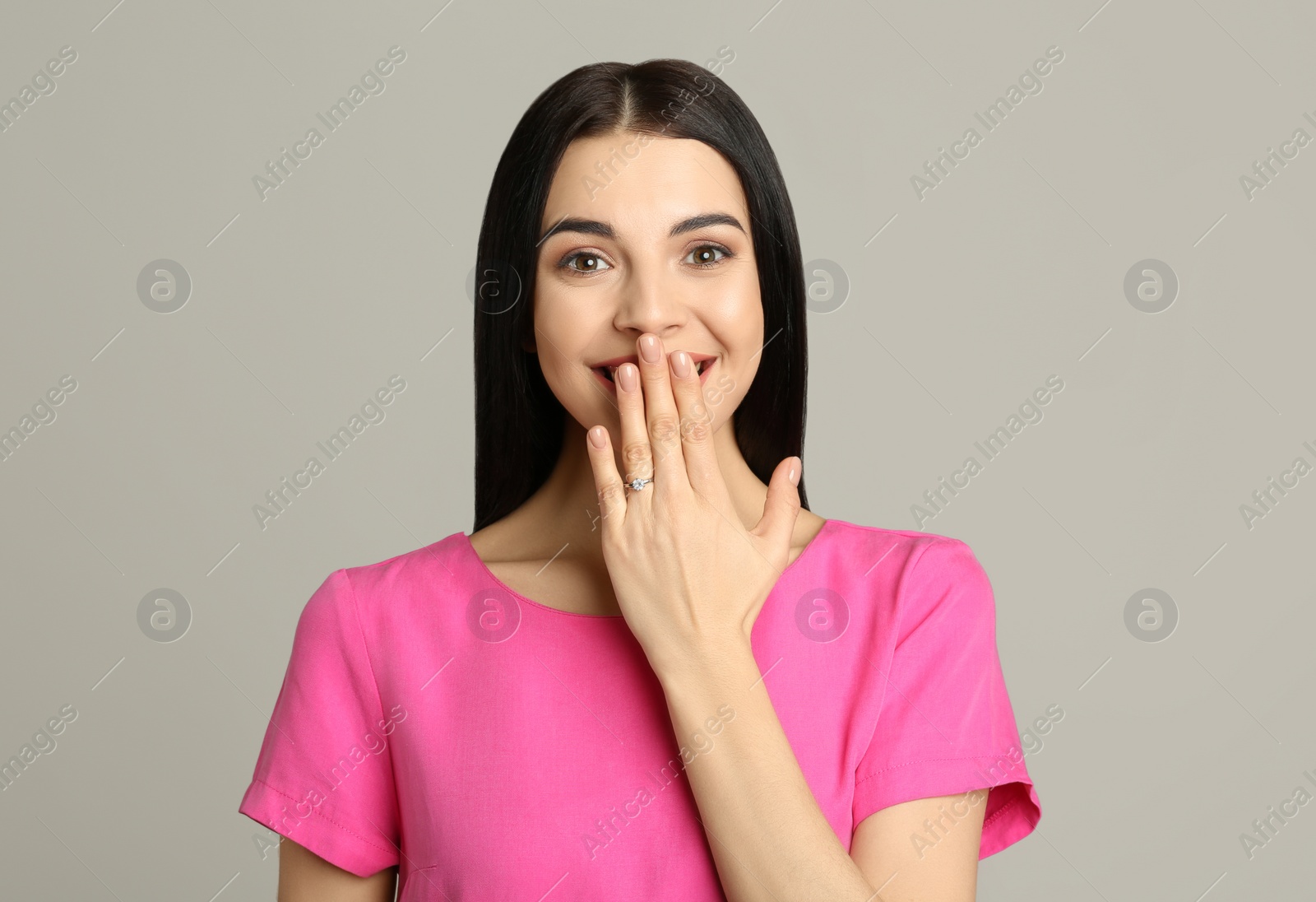 Photo of Happy young woman wearing beautiful engagement ring on grey background